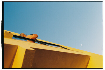 Man Leaning from Yellow Building with Moon