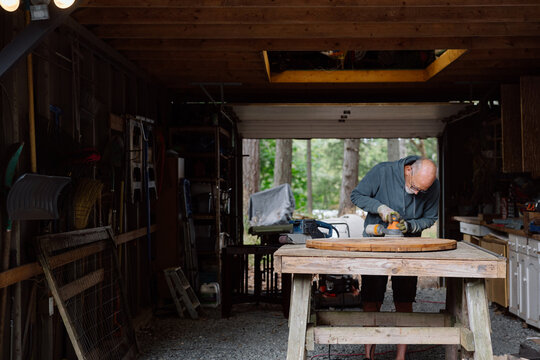 Candid moment of an elderly man woodworking in a garage
