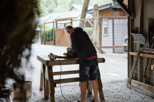 Woodworker at a rustic outdoor workshop shaping wood on a bench