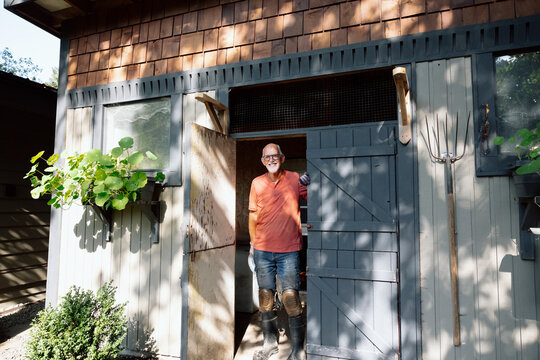 Older man stands in rustic shed doorway, ready to work