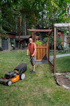 Candid backyard scene: man mowing lawn with knee brace