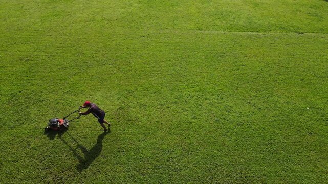 Drone Footage of Groundskeeper Mowing Grass on a Football Field