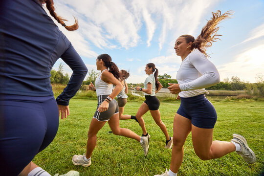 Group of women running together in a park during a sunny day