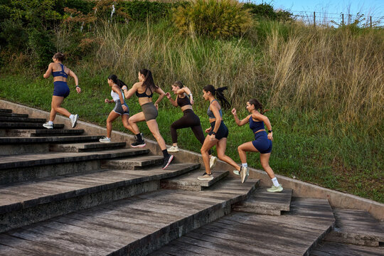 Women run up outdoor stairs in a scenic park setting