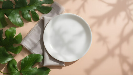White plate on beige napkin with tropical leaves on peach background, styled for natural and elegant dining visuals.