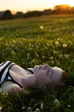 A serene outdoor portrait of a young woman with lying in grass