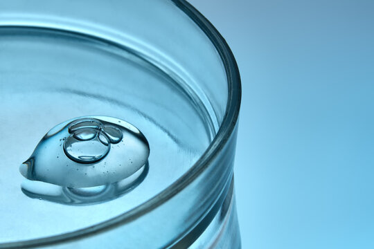 Droplet of Face Serum In Petri Dish on Blue Background with Copy Space