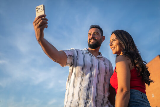 Young couple taking selfie with blue sky background