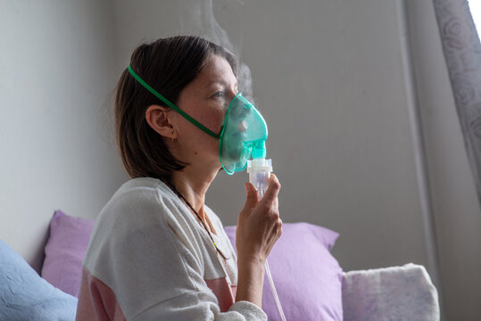 Woman with a nibulaise mask inhales. Steam of the medicine