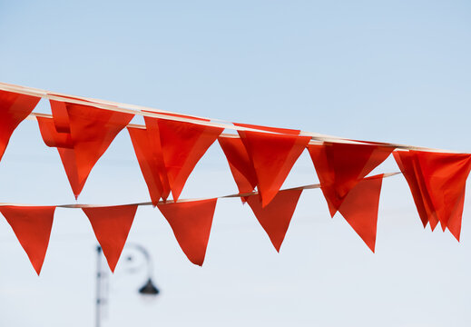 Bright Orange Flags Adorn a Clear Sky During a Festive Event