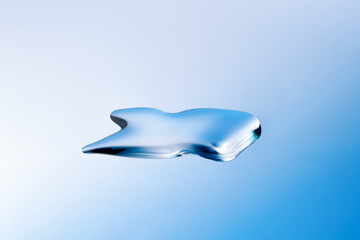 Droplet of fluid face serum on light blue gradient backdrop.