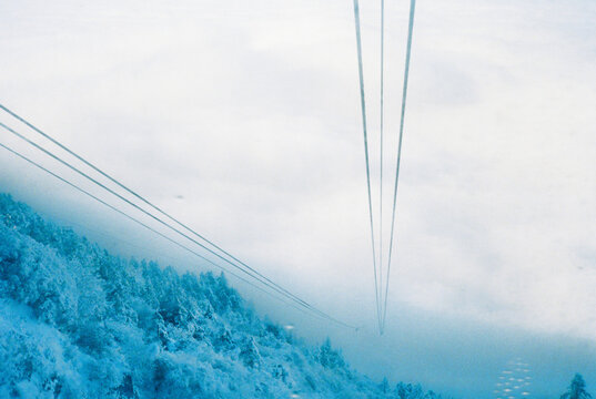 A downhill view of a mountain and thick white clouds.