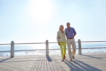 Hug, sea and senior couple on vacation, love and mockup space on promenade. Elderly man, woman and holiday by ocean for healthy relationship, walk and embrace with smile for romance in retirement