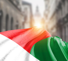 Madagascar  flag fluttering on blur street with building. Madagascar national flag for independence day.