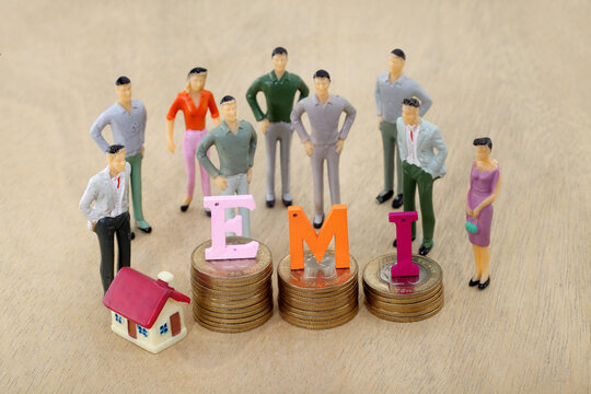 Model house,figurines and Equated Monthly Installment EMI letters on coin towers 