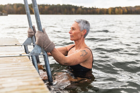 Active Mature Woman Climbing Ladder from Cold Lake