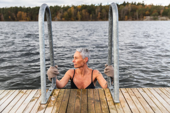 Woman Relaxing in Cold Lake Water from Wooden Dock