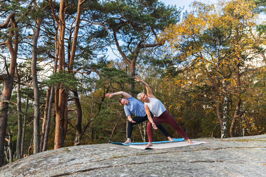 Two Women Practicing Yoga Poses on a Rock in Nature