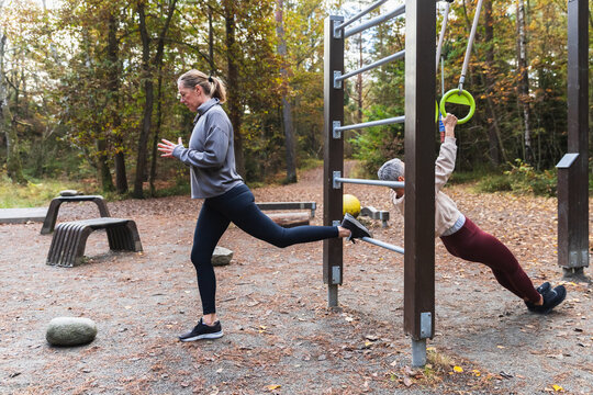 Two Women Training with Single-Leg Squats and Ring Rows Outdoors
