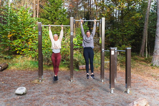 Two Friends Hanging from a Pull-up Bar at an Outdoor Gym