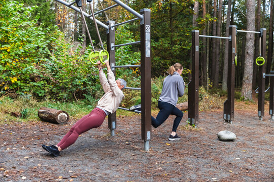 Two Women Training with Single-Leg Squats and Ring Rows Outdoors