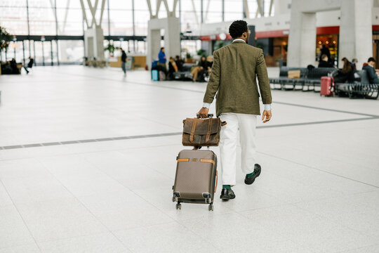 Businessman Walking With Luggage in Modern Airport Terminal Interior