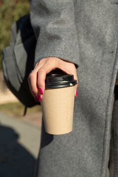 Woman holding takeaway coffee paper cup outdoors