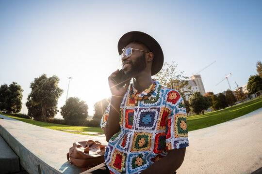 Stylish Black man talking on phone in park