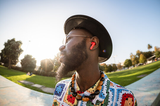 Black man wearing wireless earbuds enjoying music in park