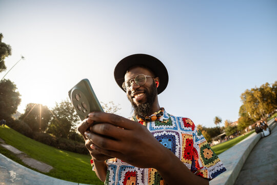 African American man smiling using smartphone outdoors