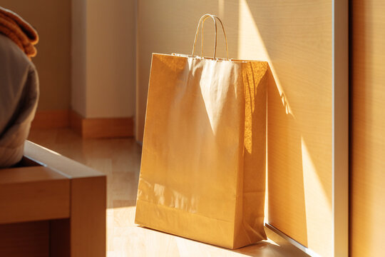 Sunlit paper shopping bag by the wall in a cozy room