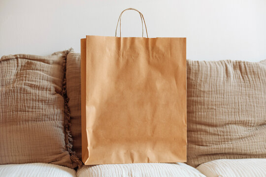 Brown paper shopping bag resting on a sofa in a cozy setting
