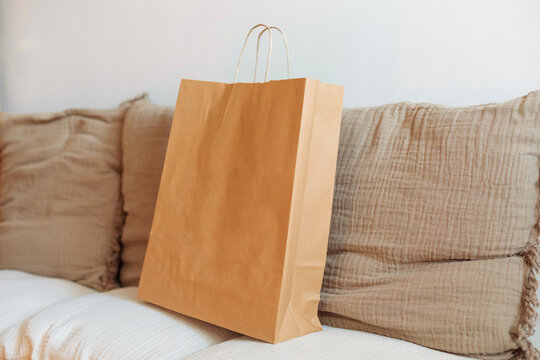 Brown paper shopping bag resting on a sofa in a cozy setting