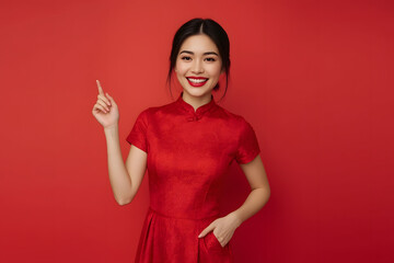 Woman in cheongsam posing while pointing up against red background