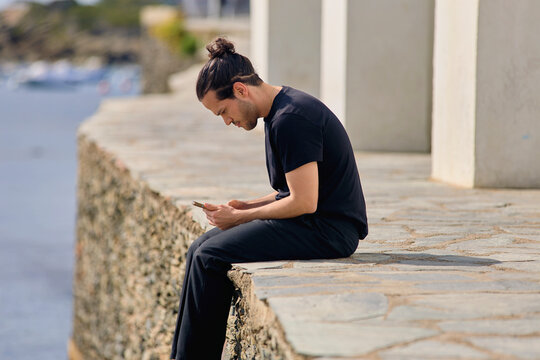 Man sitting by the sea using smartphone in Cadaqu&eacute;s Spain