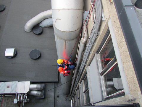 Worker Rappelling Down a Tall Building While Performing Maintenance