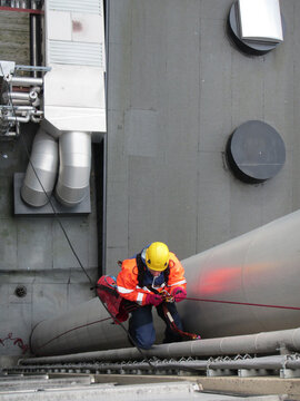 Worker in Safety Gear Climbing Tall Structure in Industry