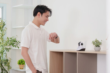 Technology and Lifestyle. Young man interacting with smart home device while checking his smartwatch.