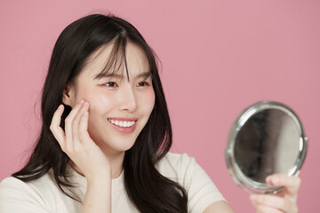 Wellness Beauty. Happy woman admiring her reflection while applying skincare.