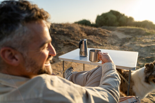Camper enjoying coffee with dog outdoors