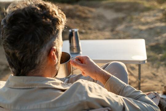 Man drinking coffee at seaside campsite - Powered by Adobe