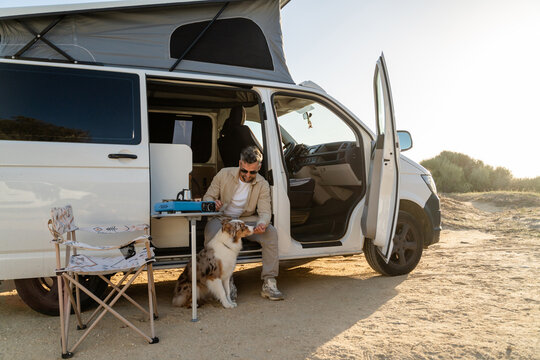 Traveler relaxing with dog near camper