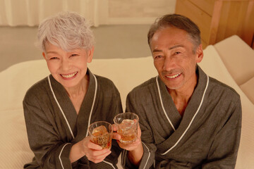 寝室でウイスキーを飲むシニア夫婦　ポートレート　カメラ目線