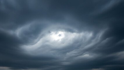 Obraz premium Dramatic dark blue storm clouds filling the sky with a bright light eye breaking through the ominous atmosphere
