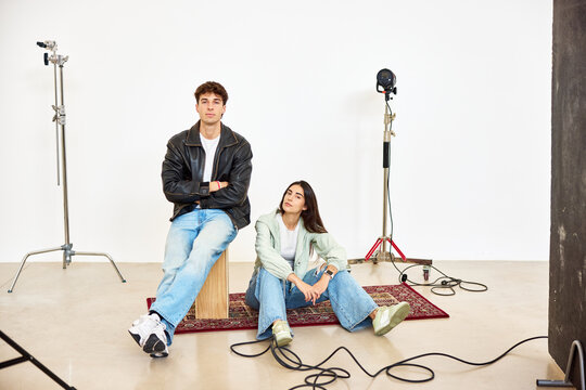 Stylish young duo poses in studio setting with lighting equipmen