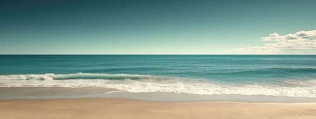 Calm beach waves, tan sand, blue water under clear sky