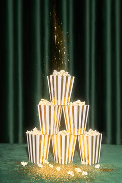 Stacked popcorn containers with falling glitter on green background