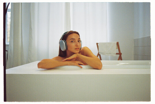 Woman relaxing in a serene bathroom with headphones listening music