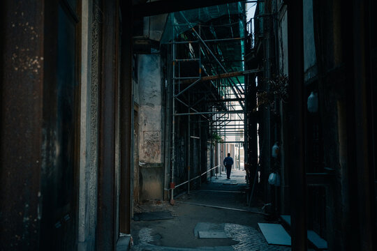 Dark Alley With Construction Scaffolding and a Person Walking