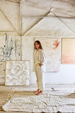 Creative artist poses in a bright studio with abstract art